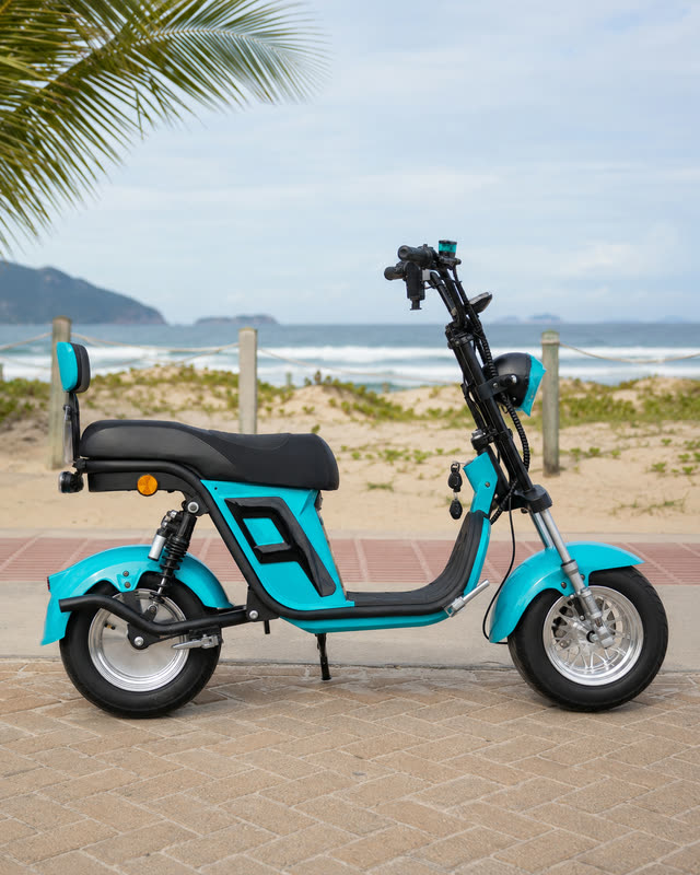 Perfil lateral completo da scooter elétrica X12 azul turquesa, estacionada no calçadão em frente à praia.
